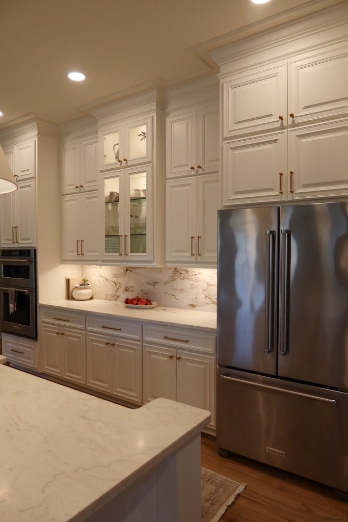 bright kitchen with white cabinets, gold knobs, under cabinet lighting and a white quartz countertop