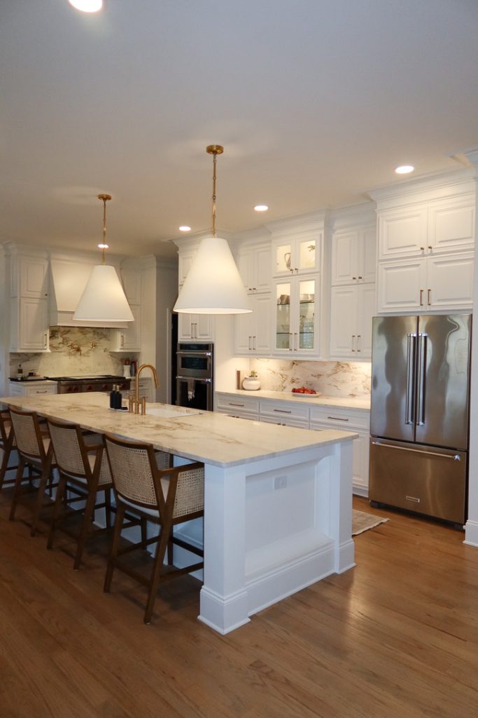 bright kitchen with white cabinets, gold knobs, under cabinet lighting and a white quartz countertop