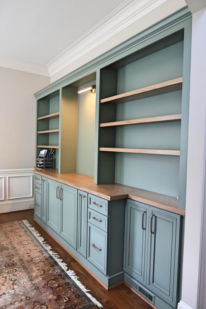 bookshelf with sage green cabinetry with stained wood countertops