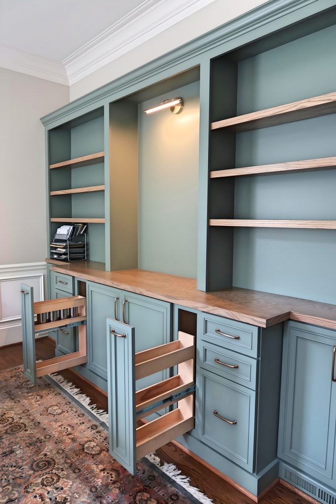 bookshelf with sage green cabinetry with stained wood countertops and drawers open