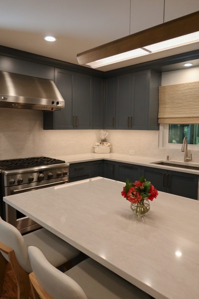 photo centered on white quartz island with deep blue kitchen cabinets in back