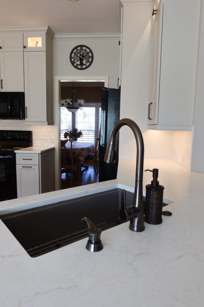 vertical shot of black faucet with large work station sink