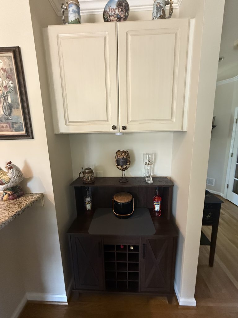 vertical shot of wet bar with white wood cabinets and black countertops
