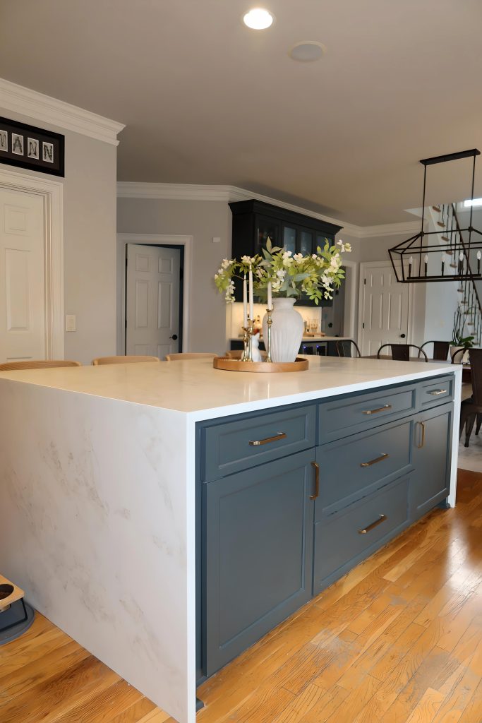 modern white kitchen with waterfall quartz island and blue cabinetry