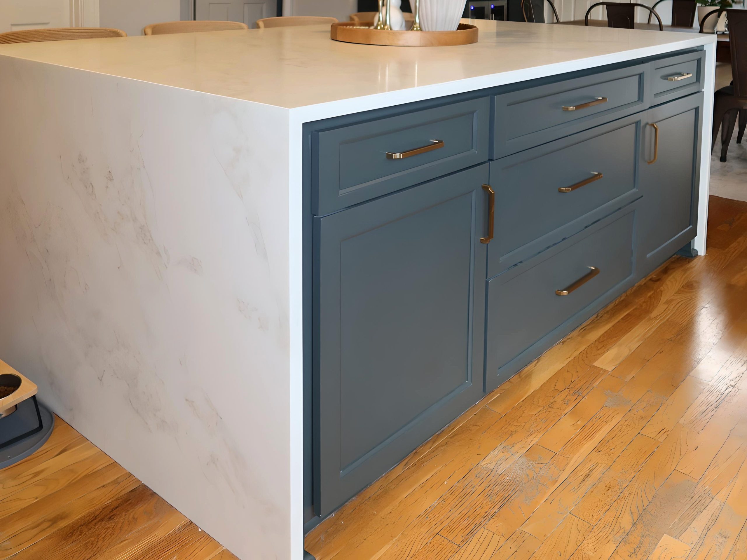 modern white kitchen with waterfall quartz island and blue cabinetry