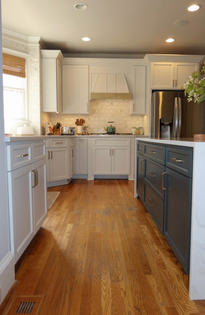 modern white kitchen with waterfall quartz island and blue cabinetry