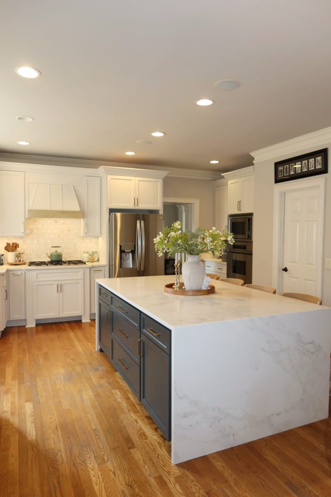modern white kitchen with waterfall quartz island and blue cabinets