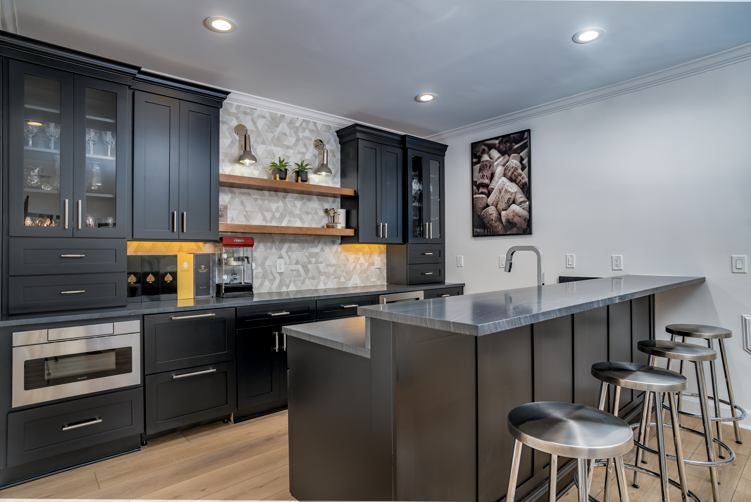 kitchenette in basement with black cabinetry and under cabinet lighting