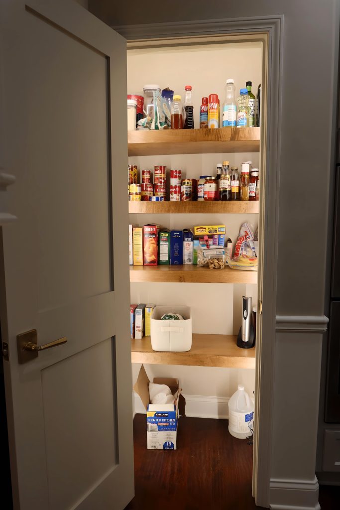 a lit kitchen pantry with stained shelving