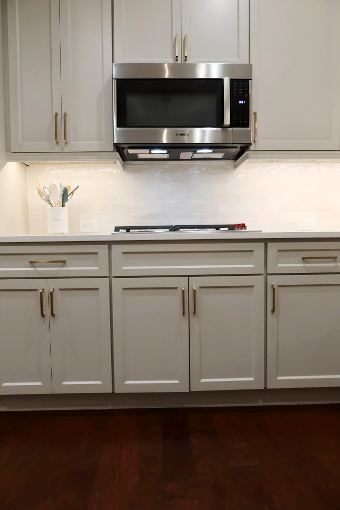 Modern kitchen with light neutral cabinetry, quartz countertops, and built-in stainless steel appliances