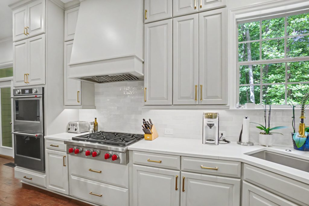 Modern white kitchen with white cabinetry and white countertop and white hood