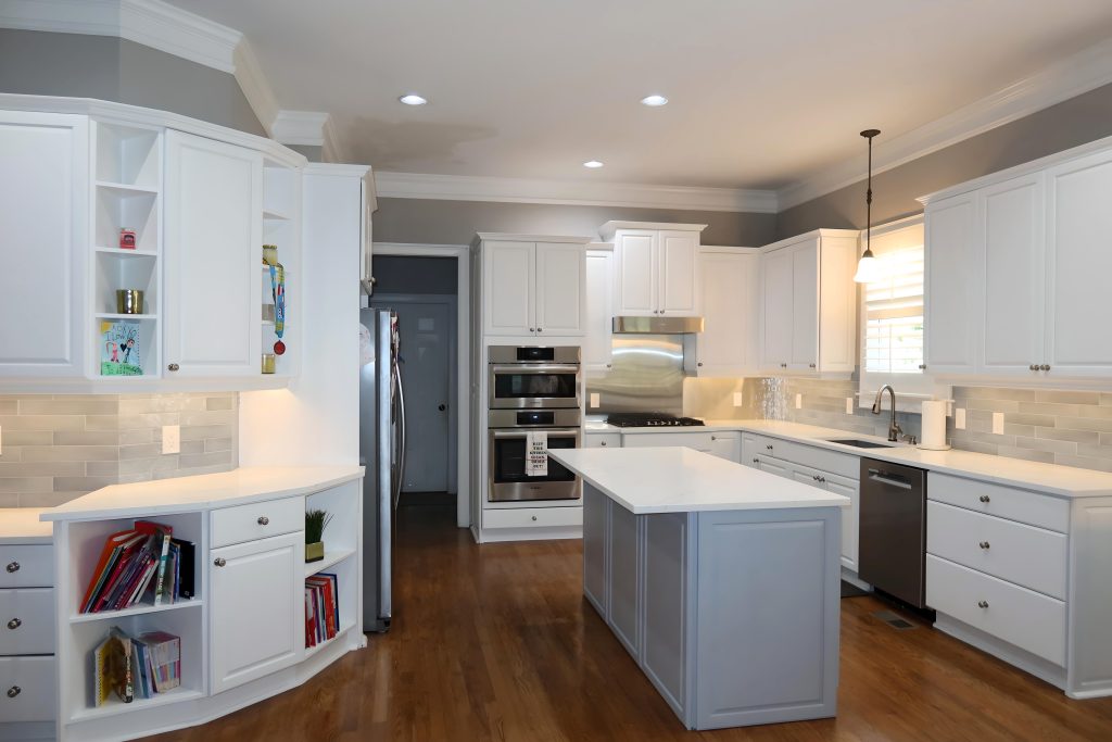 Bright white kitchen with blue island, white quartz countertops, and stainless steel appliances