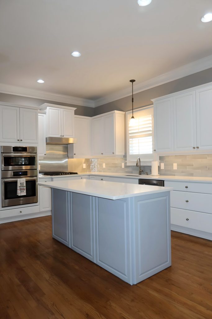 Bright white kitchen with blue island, white quartz countertops, and stainless steel appliances