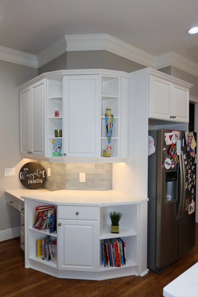 White kitchen cabinetry with built-in open shelving, quartz countertop, and under-cabinet lighting