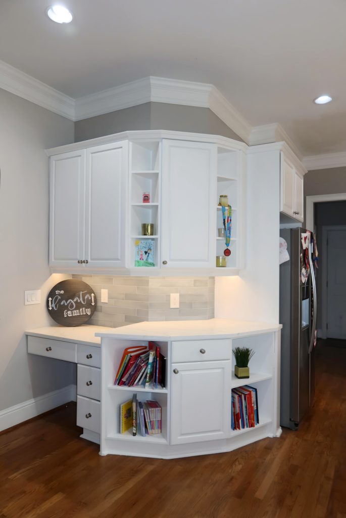 White kitchen cabinetry with built-in open shelving, quartz countertop, and under-cabinet lighting