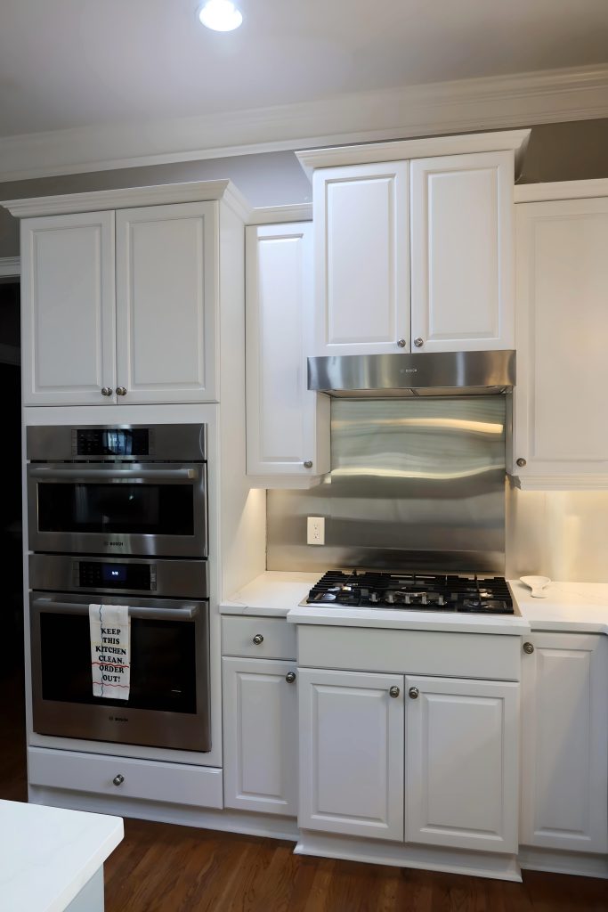 remodeled kitchen with white cabinets and stainless steel appliances and backsplash