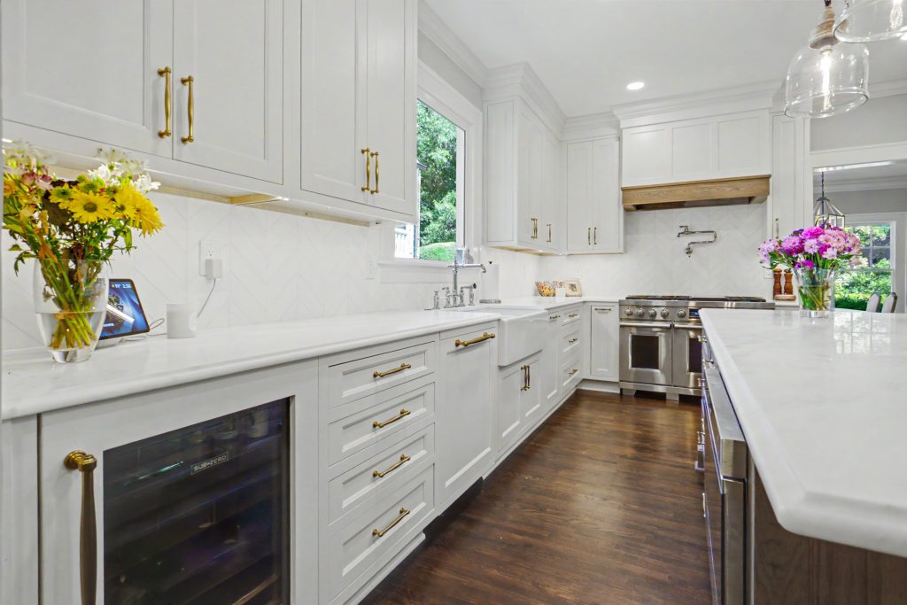 White inset kitchen cabinets with beverage cooler, brass hardware and quartz countertops