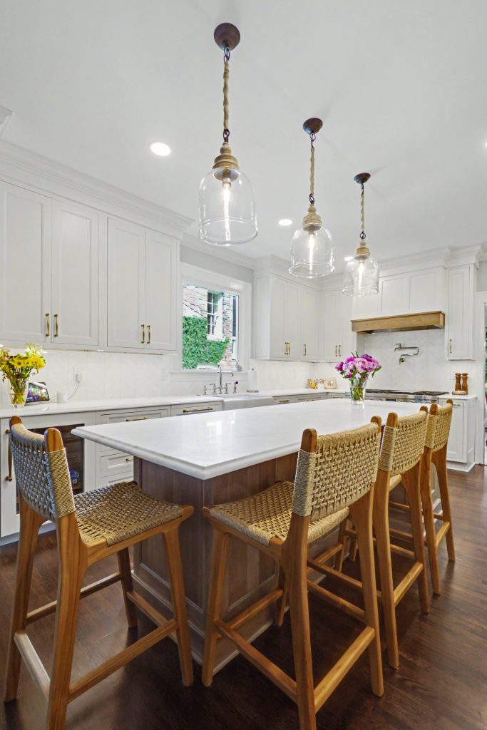 White inset kitchen cabinetry with large wood island and counter seating