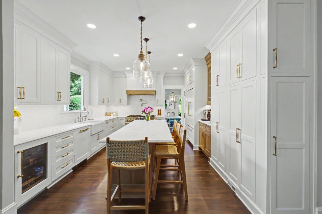Classic white kitchen with floor-to-ceiling cabinetry, warm wood island and brass accents