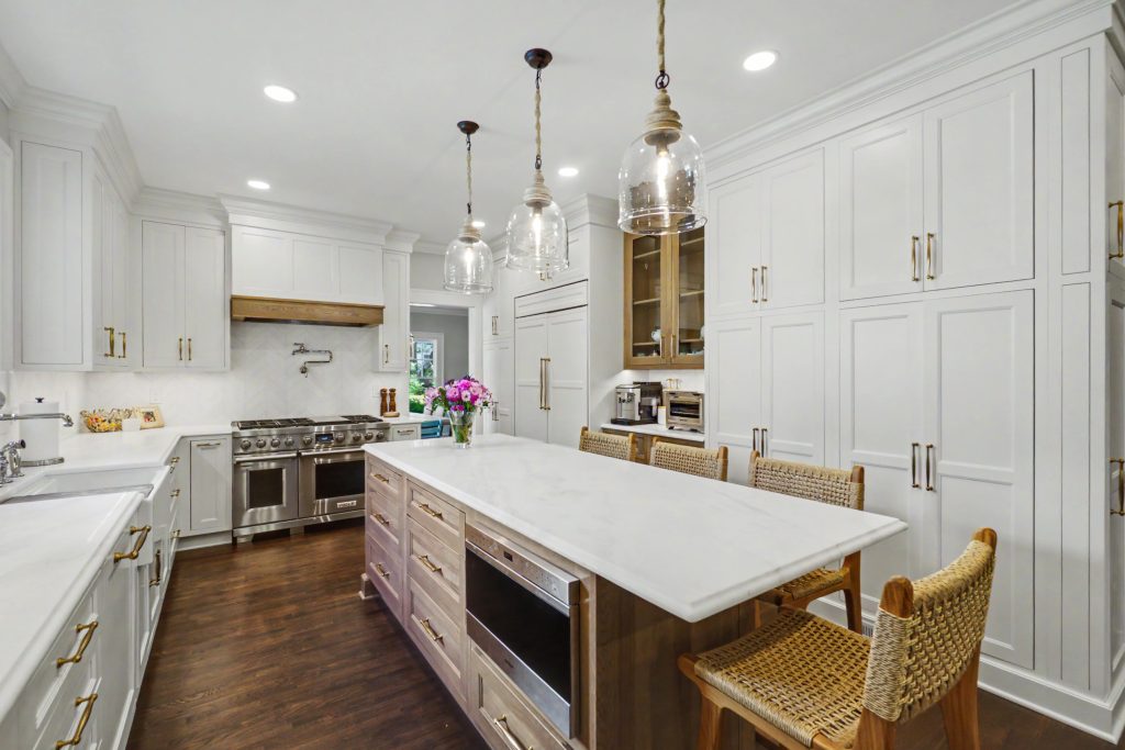Finished kitchen remodel with white cabinetry, wood island and integrated appliances