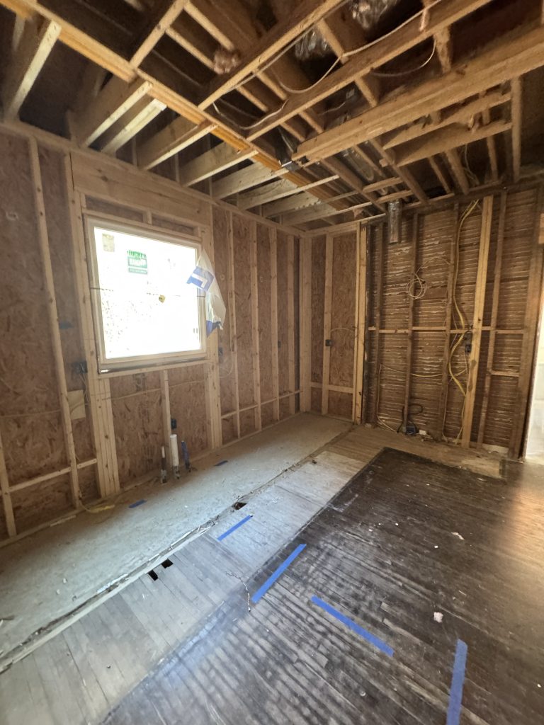 Bare kitchen interior with exposed framing before renovation